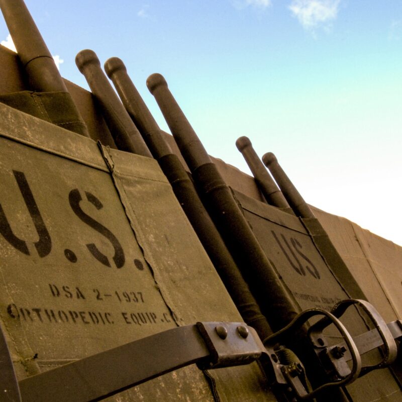 A stack of antique 1937 U.S. military stretchers, showing the heavy wood and canvas materials used before the era of lightweight composites and modern military composite inspection.