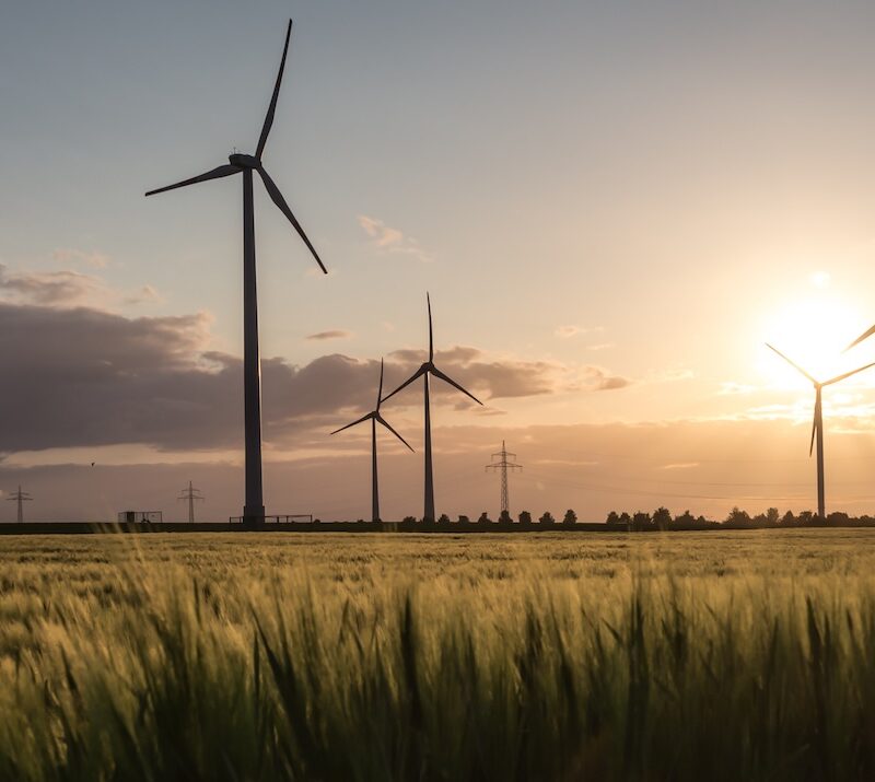 A scenic view of a wind farm at sunset, highlighting the massive turbines that require regular wind blade inspection to operate safely and efficiently.