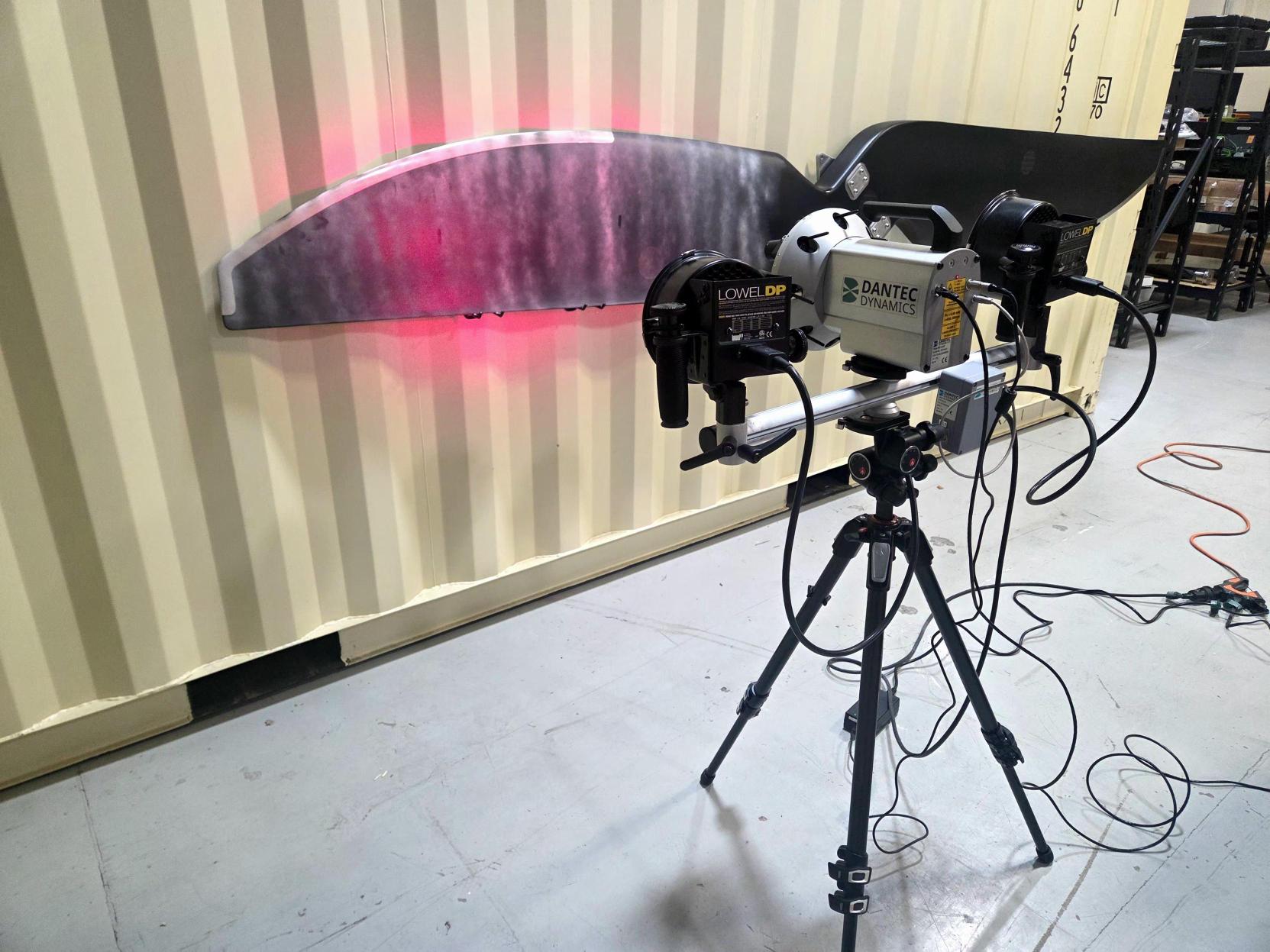 Laser shearography NDT inspection system scanning a composite panel with red laser illumination