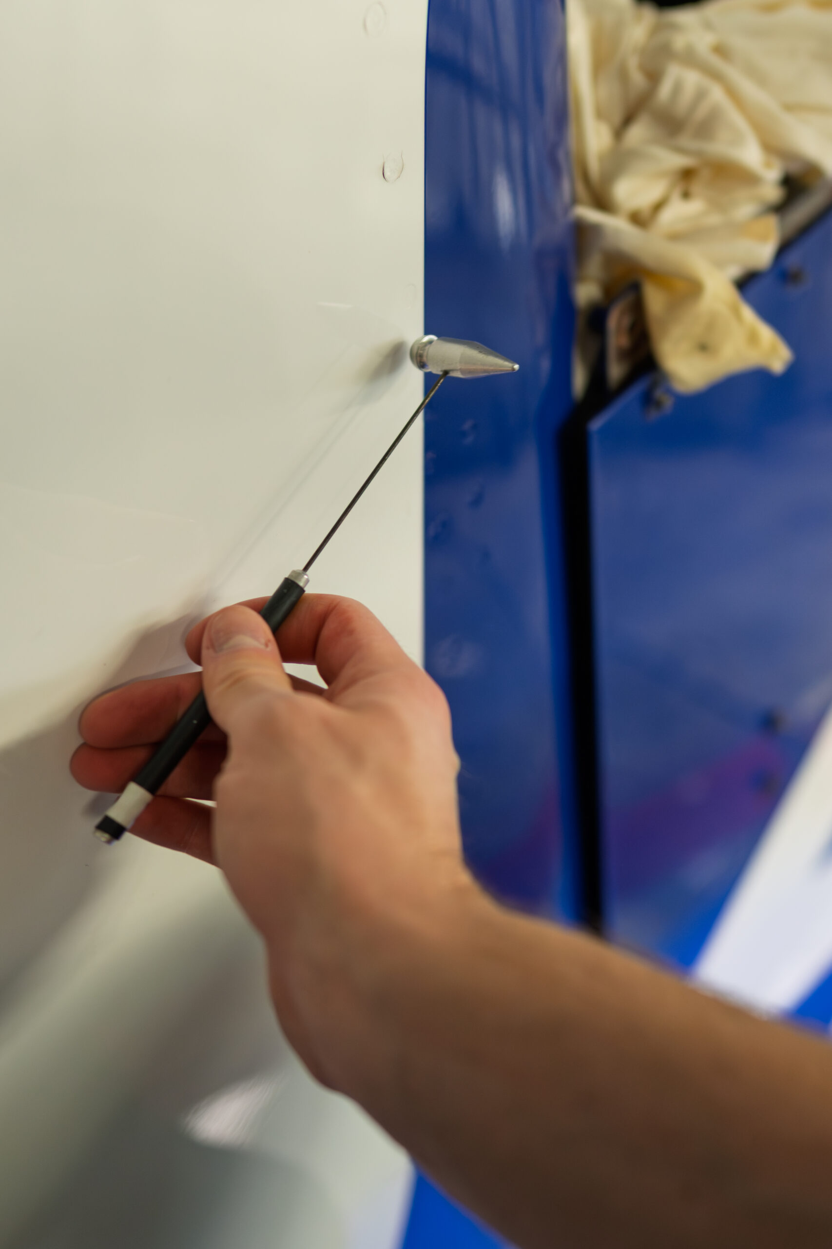 Technician performing tap testing on a composite structure to identify delaminations, disbonds, and internal defects during NDT inspection.