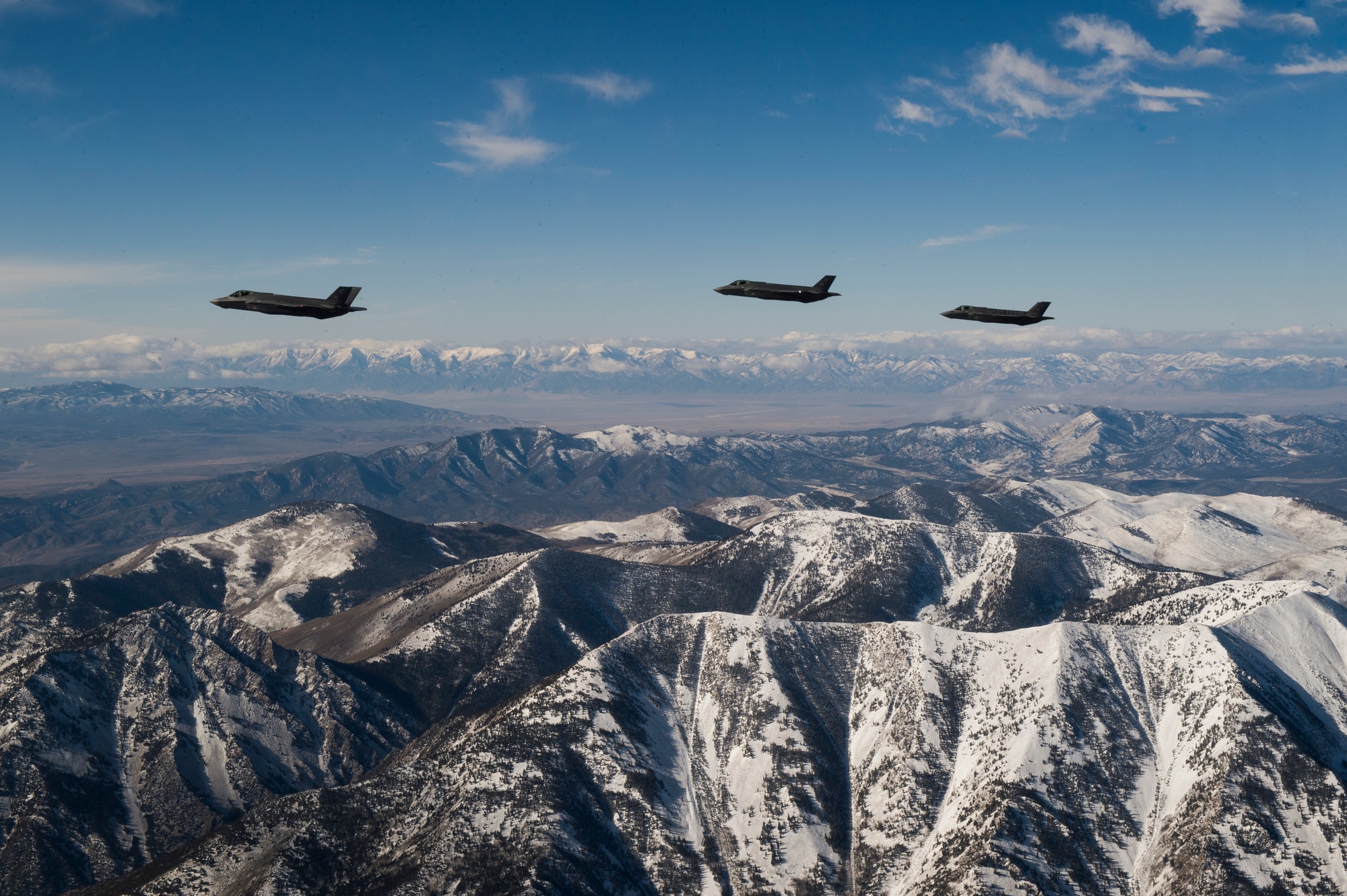 Three F-35A Lightning II fighters from Hill Air Force Base flying over snow-covered Utah mountains, illustrating CUI protection for F-35 program data